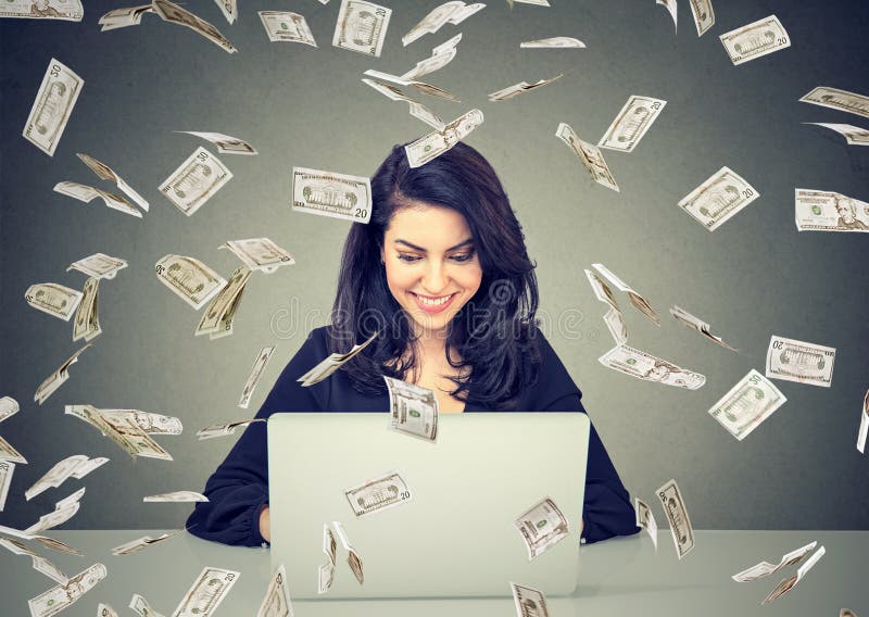Happy woman using a laptop building online business under dollar bills falling down. Money rain IT entrepreneur success economy concept royalty free stock photography