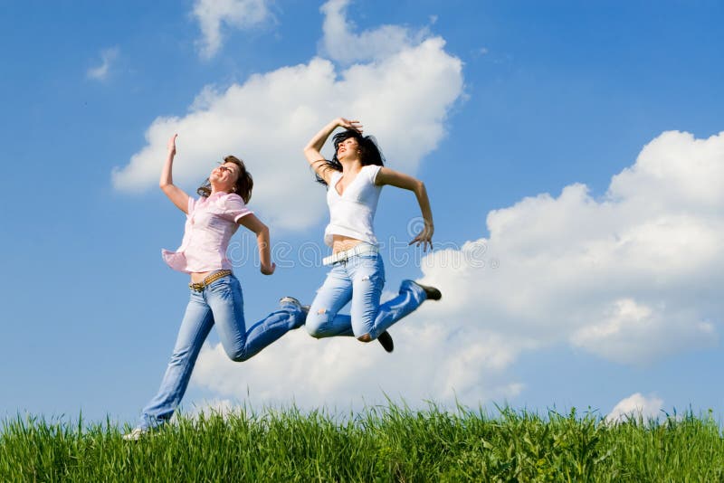 Happy women jumping on the green grass