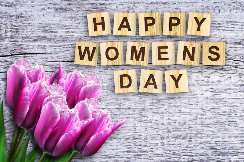 Happy womens day, the inscription consists of the alphabet on wooden cubes. Beautiful tulips. Wooden background