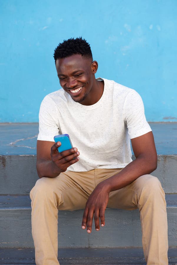 Happy young african man sitting on steps and using phone royalty free stock photo Happy young african man sitting on steps and using phone royalty free stock photo