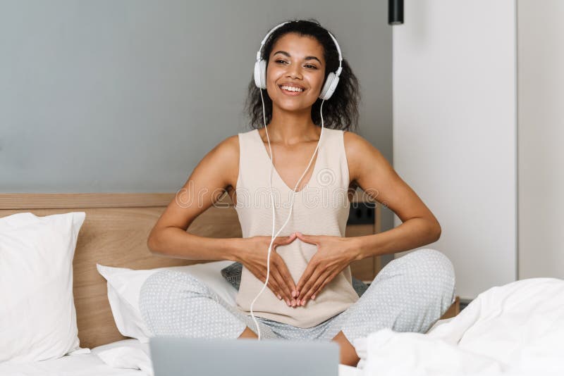 Cheerful Young African Woman Holding A Pillow And Sitting On The