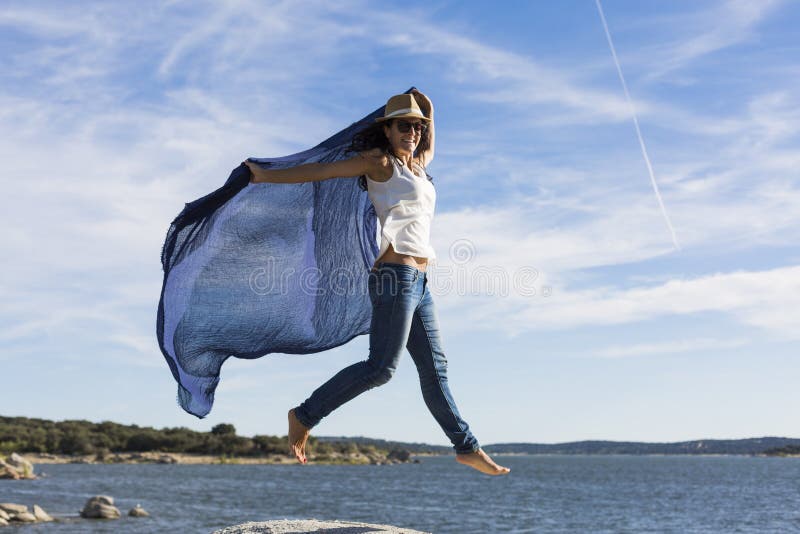 happy young beautiful woman playing with a blue shawl at the beach. Fun, wind and lifestyle