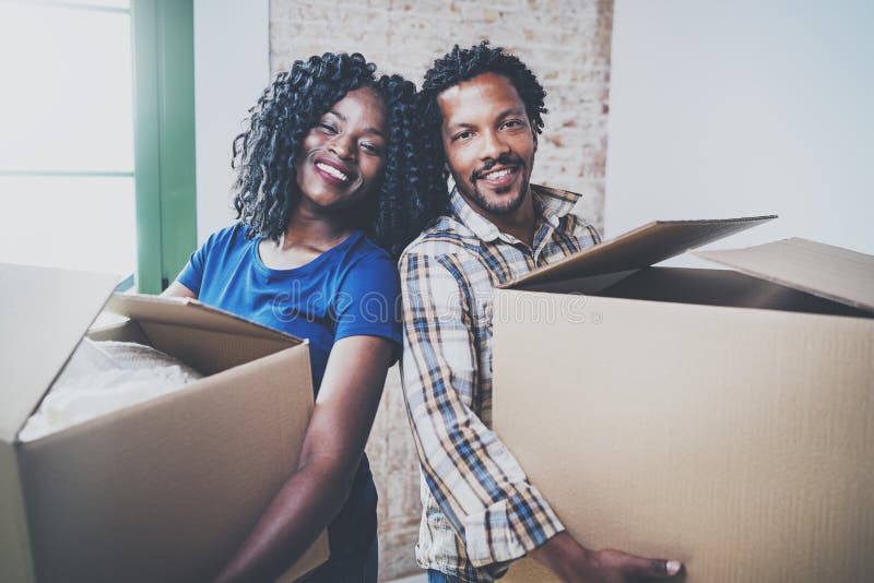 Happy young black african man and his girlfriend moving boxes into new house together and making a successful life royalty free stock photography Happy young black african man and his girlfriend moving boxes into new house together and making a successful life royalty free stock photography