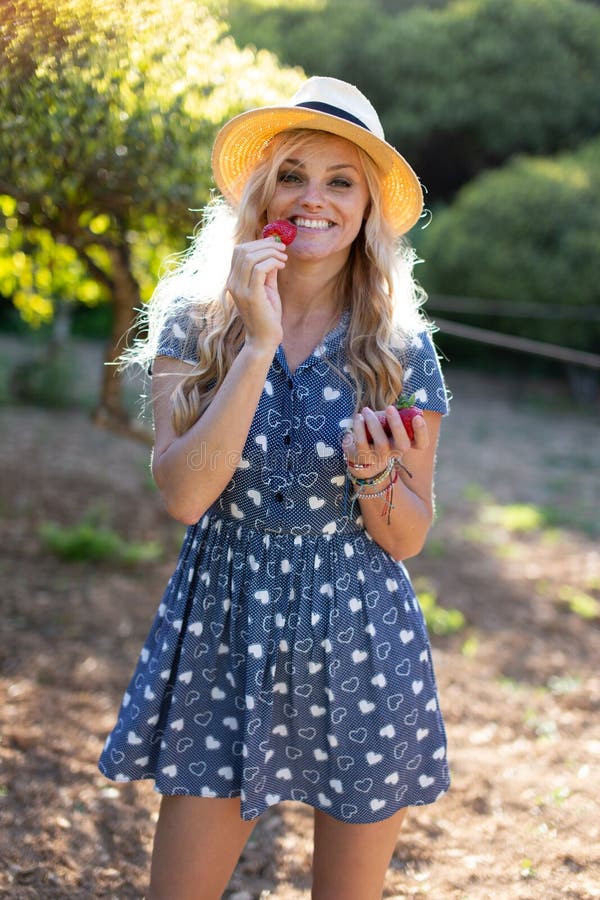 Young Blonde Caucasian Woman Eating Strawberry Outdoors Stock Image 