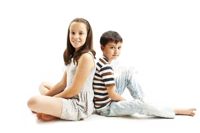 Happy young brother and sister posing back to back sitting on floor