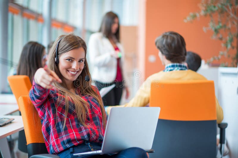 Happy young business woman with her staff, people group in background at modern bright office indoors