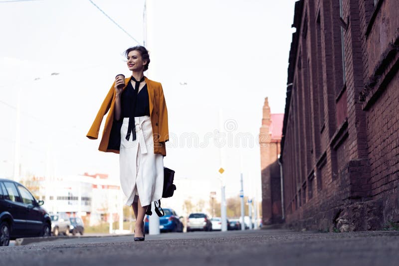 Happy young business woman walking on the street.