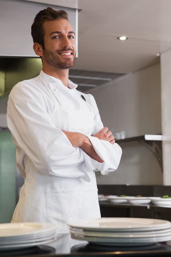 Happy young chef standing with arms crossed behind counter stock photography Happy young chef standing with arms crossed behind counter stock photography