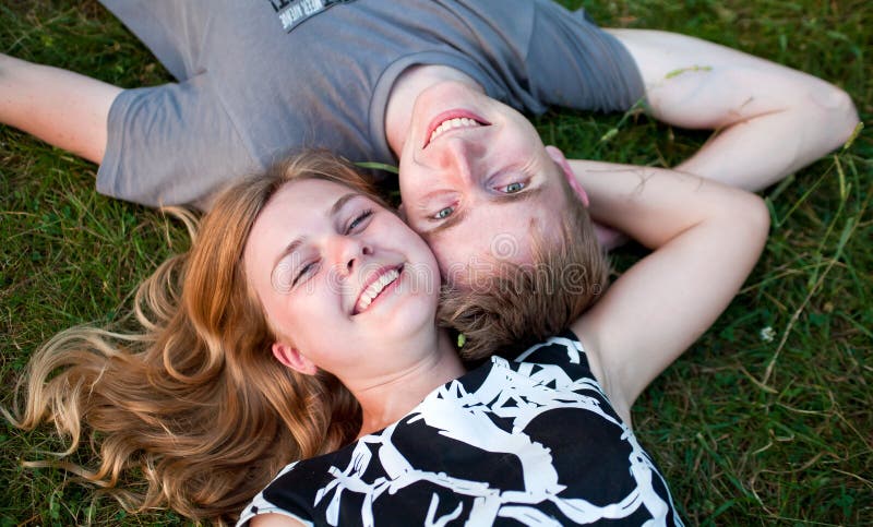 Portrait of happy young couple, laying on grass and smiling