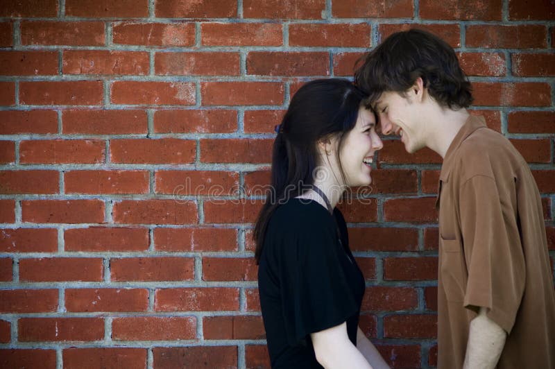 Half body portrait of happy teenage couple laughing with brick wall background. Half body portrait of happy teenage couple laughing with brick wall background.