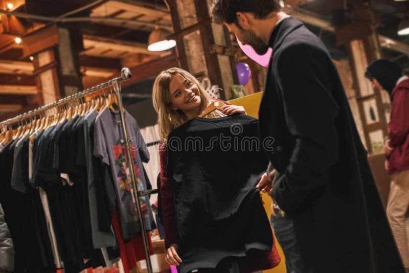 Happy young couple choosing handmade dress at small street market