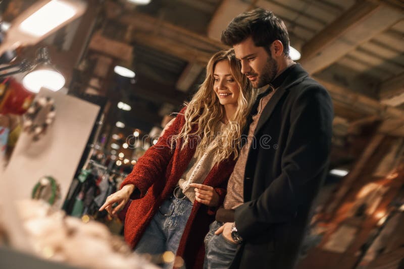 Happy young couple choosing handmade imitation jewelry at small street market