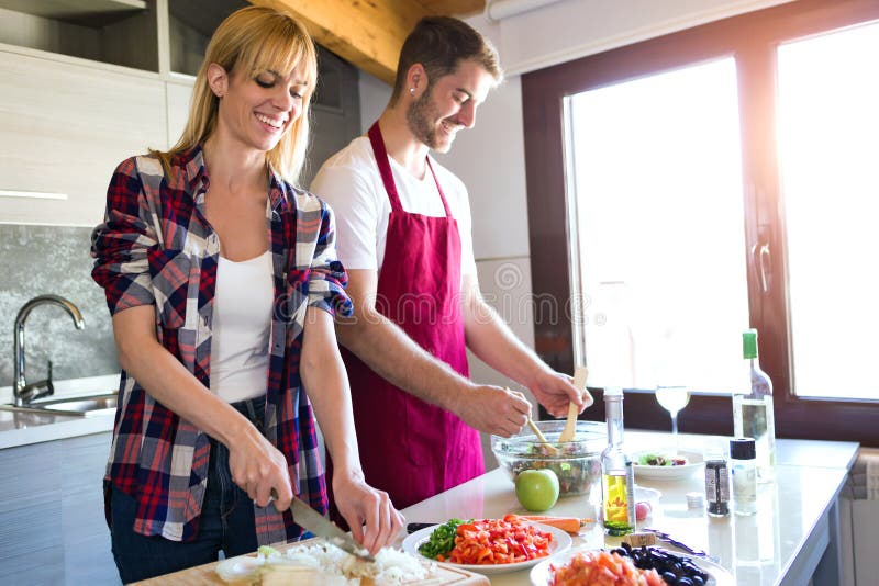 Happy young couple cooking together in the kitchen at home.