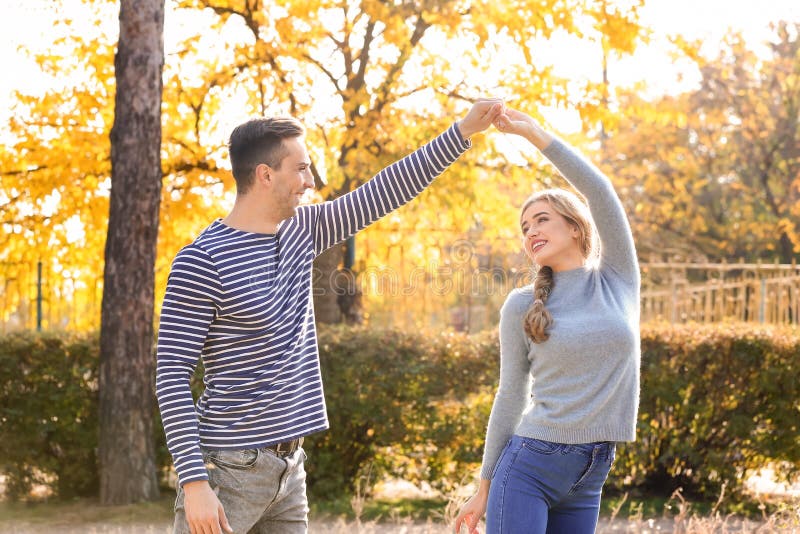 Happy young couple dancing in autumn park