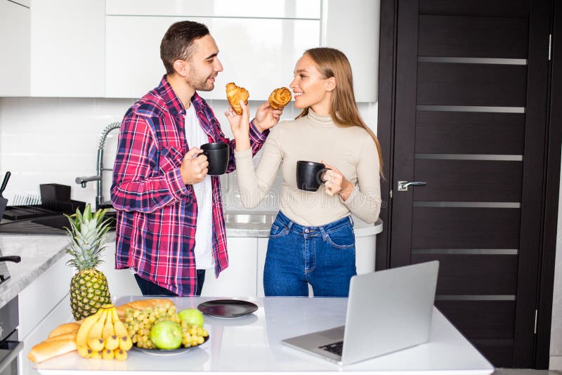 Happy young couple eating breakfast in the kitchen stock images
