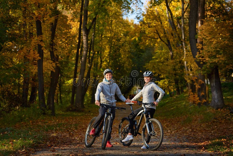 Happy young couple going for a bike ride on an autumn day in the park. royalty free stock photos Happy young couple going for a bike ride on an autumn day in the park. royalty free stock photos