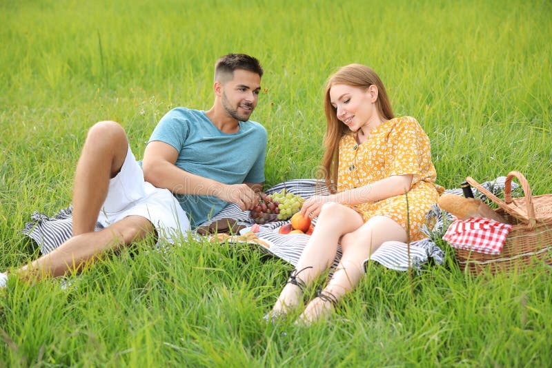 Happy young couple having picnic on green grass