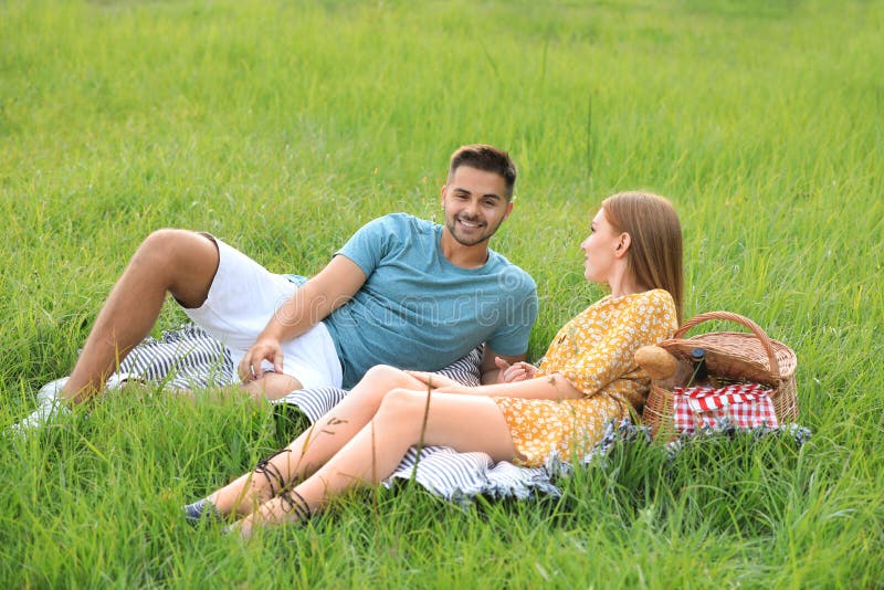 Happy young couple having picnic on green grass