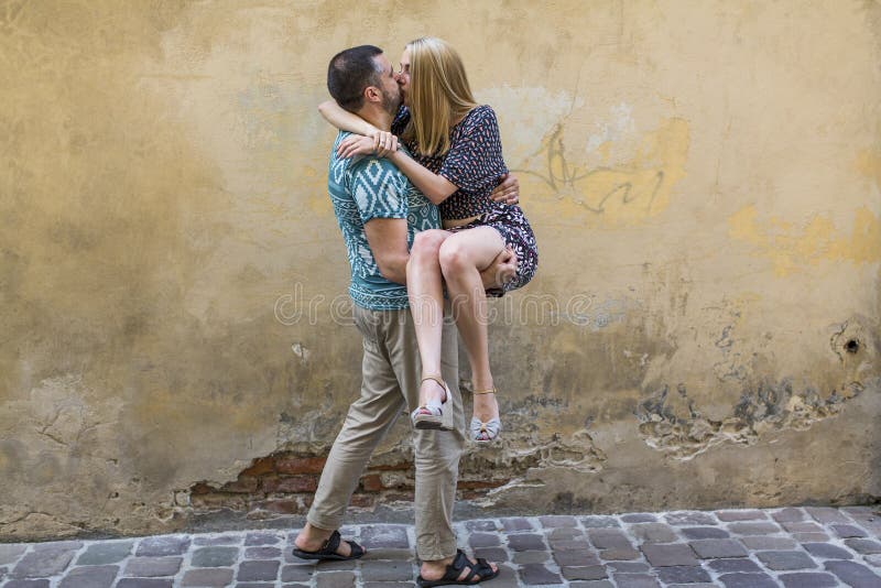 Happy Young Couple In Love Having Fun Against The Wall Of The House