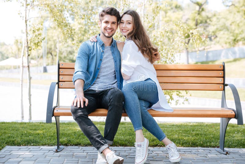 Happy young couple in love sitting on a park bench