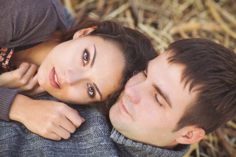 Happy young couple lying down smiling at autumn background