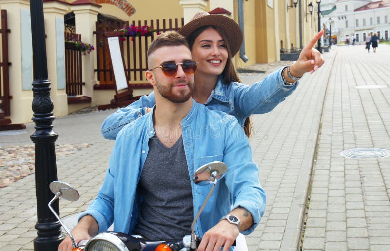 Happy young couple riding scooter in town. Handsome guy and young woman travel. Adventure and vacations concept. royalty free stock images Happy young couple riding scooter in town. Handsome guy and young woman travel. Adventure and vacations concept. royalty free stock images