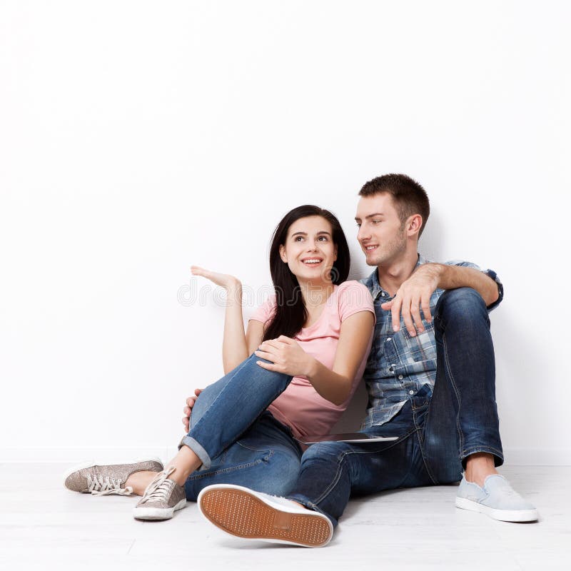 Happy young couple sitting on floor looking up while dreaming their new home and furnishing. Mock up stock image Happy young couple sitting on floor looking up while dreaming their new home and furnishing. Mock up stock image