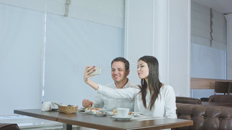 Happy young couple taking selfies with food on smartphone at a restaurant stock images Happy young couple taking selfies with food on smartphone at a restaurant stock images