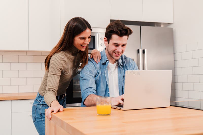 Happy young couple using a laptop and watching at notebook screen browsing internet enjoying leisure time at home royalty free stock photo