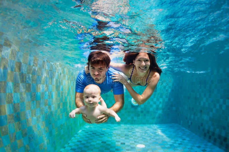 Happy young family dive underwater in swimming pool