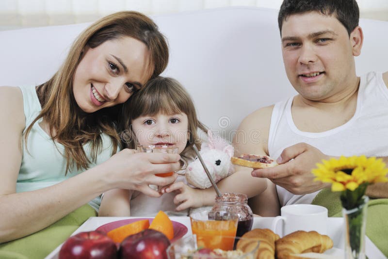 Happy young family eat breakfast in bed