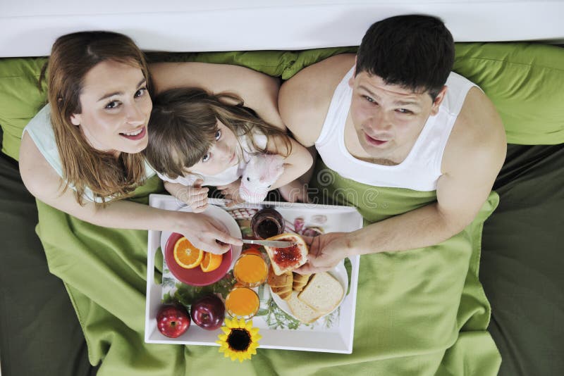 Happy young family eat breakfast in bed