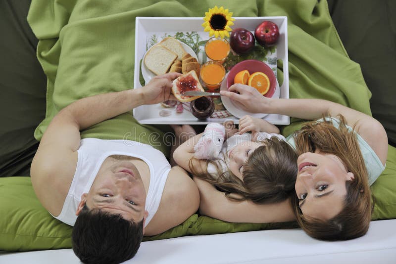 Happy young family eat breakfast in bed