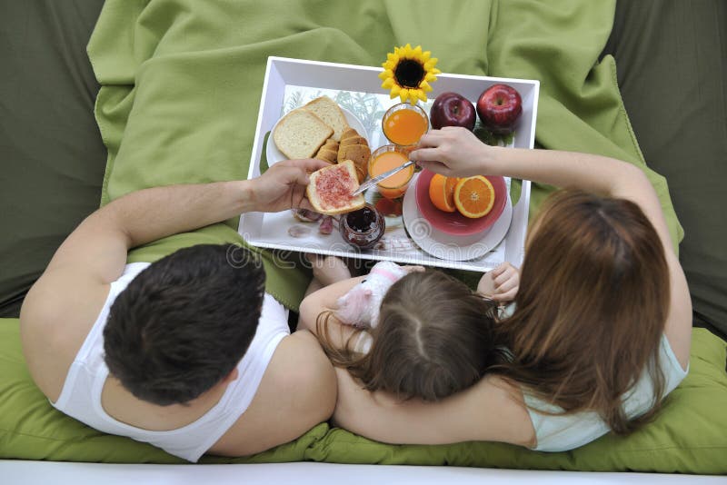 Happy young family eat breakfast in bed