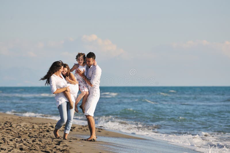 Šťastná mladá rodina v bílé oblečení pobavit na dovolenou na krásné pláži.