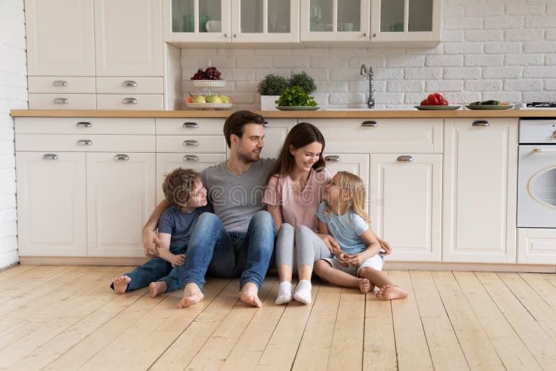 Happy young family with kids relax on warm kitchen floor stock image Happy young family with kids relax on warm kitchen floor stock image