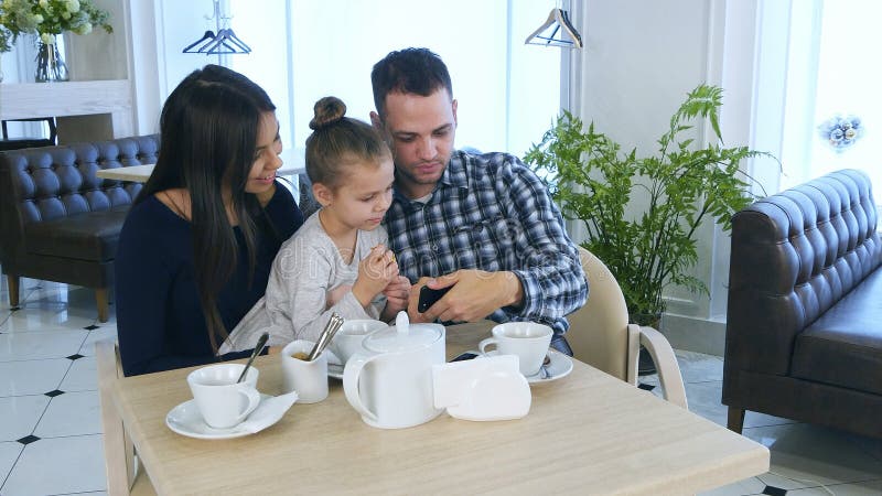 Happy young family looking at smartphone, discussing and smiling. royalty free stock image Happy young family looking at smartphone, discussing and smiling. royalty free stock image