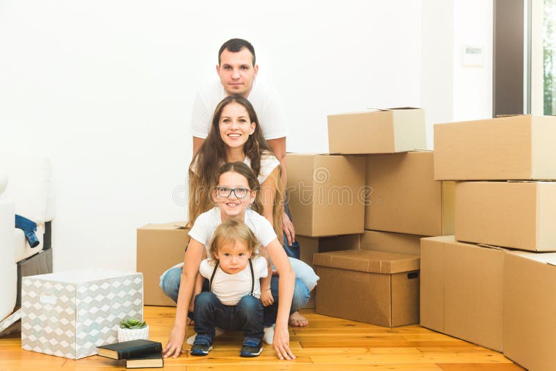 Happy young family, parents daughter and son, unpacking boxes and moving into a new home. funny kids run in with boxes