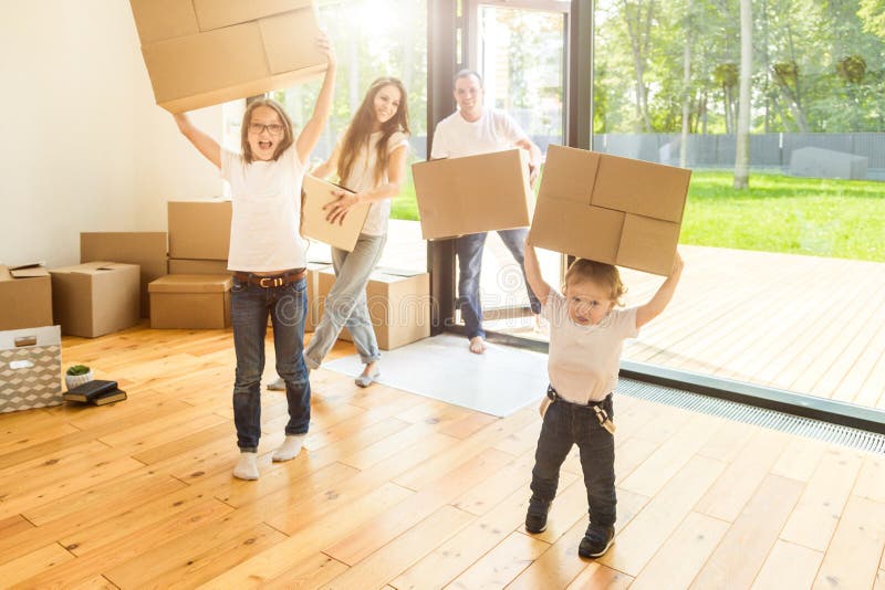 Happy young family, parents daughter and son, unpacking boxes and moving into a new home. funny kids run in with boxes