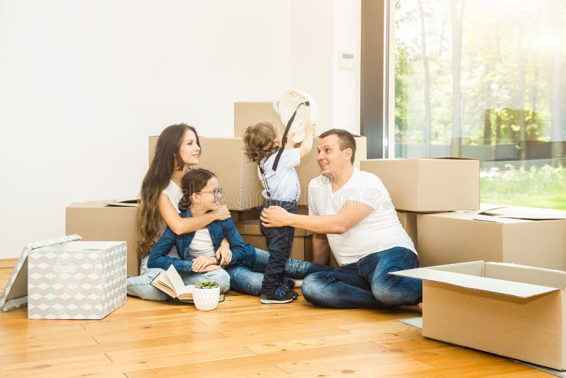 Happy young family, parents daughter and son, unpacking boxes and moving into a new home. funny kids run in with boxes