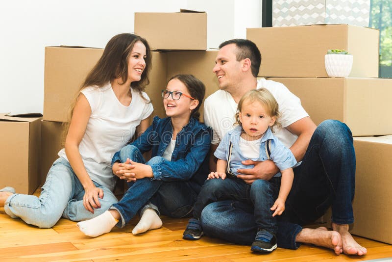 Happy young family, parents daughter and son, unpacking boxes and moving into a new home. funny kids run in with boxes