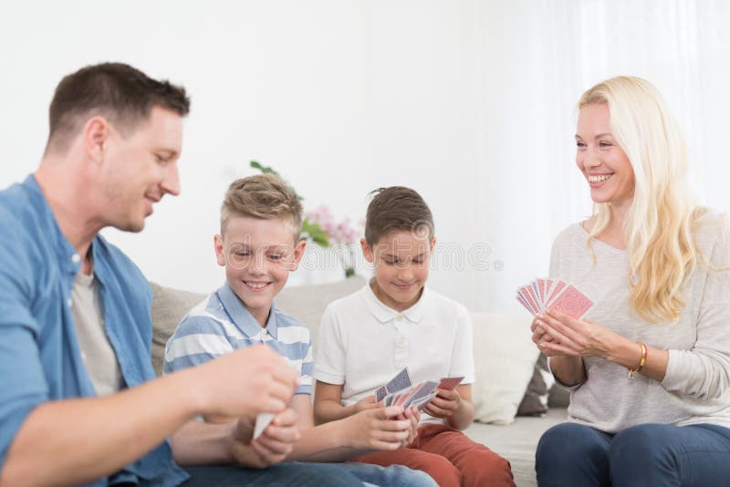 Happy young family playing card game at home.