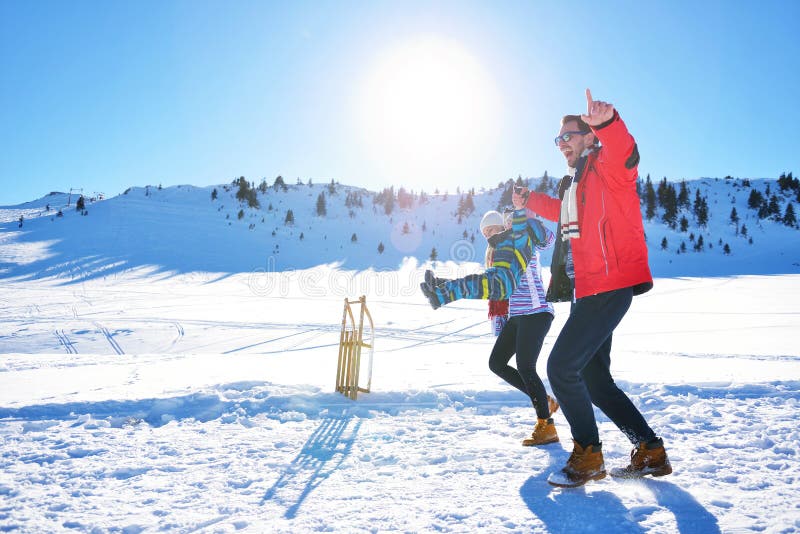 Happy young family playing in fresh snow at beautiful sunny winter day outdoor in nature. Carrot, christmas.