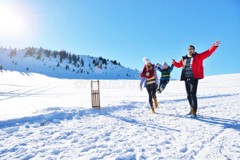 Happy young family playing in fresh snow at beautiful sunny winter day outdoor in nature