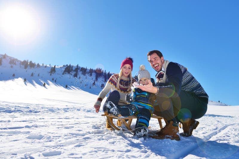 Happy young family playing in fresh snow at beautiful sunny winter day outdoor in nature. Mother, outdoors.