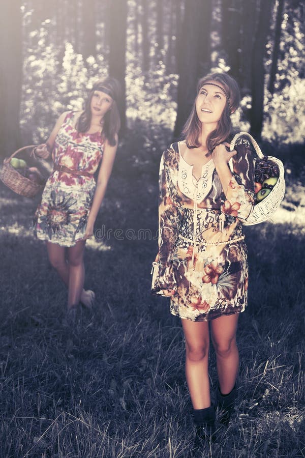 Happy young fashion girls with a fruit basket walking in summer forest stock photo Happy young fashion girls with a fruit basket walking in summer forest stock photo