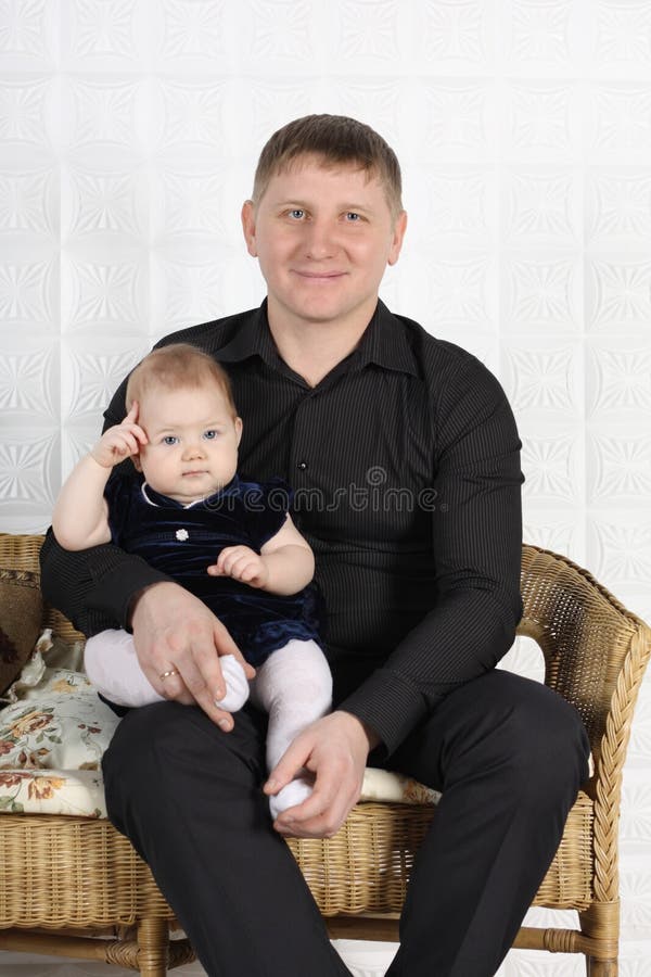 Happy young father and baby sit on sofa.