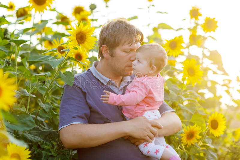 Happy young father having fun with newborn baby daughter in sunflower field on warm summer day, family portrait together royalty free stock photo Happy young father having fun with newborn baby daughter in sunflower field on warm summer day, family portrait together royalty free stock photo