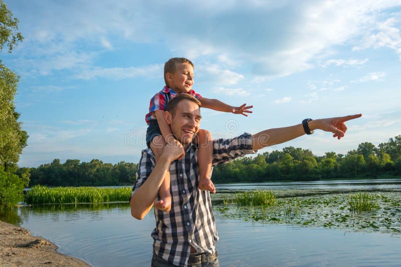 Happy young father holds his son piggyback ride on his shoulders stock photography Happy young father holds his son piggyback ride on his shoulders stock photography