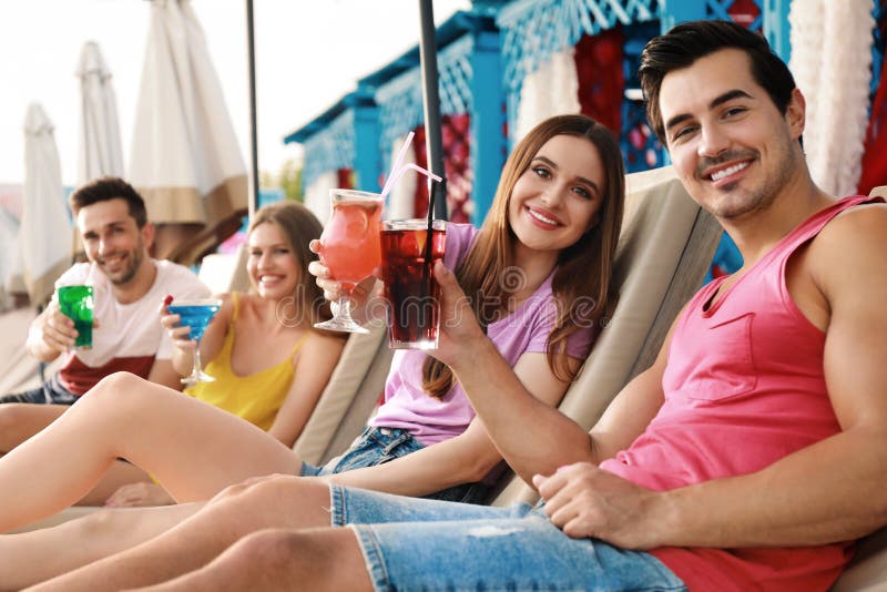 Happy young friends with fresh summer cocktails on sunbeds stock photography Happy young friends with fresh summer cocktails on sunbeds stock photography
